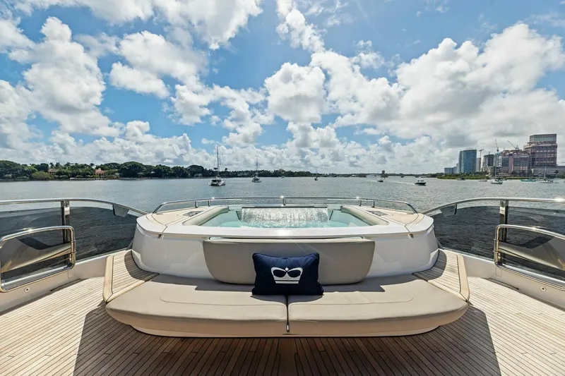 Lady Lion Yacht Photos Pics Luxurious 2023 Princess X95 yacht deck with jacuzzi, overlooking serene waterfront and city skyline.