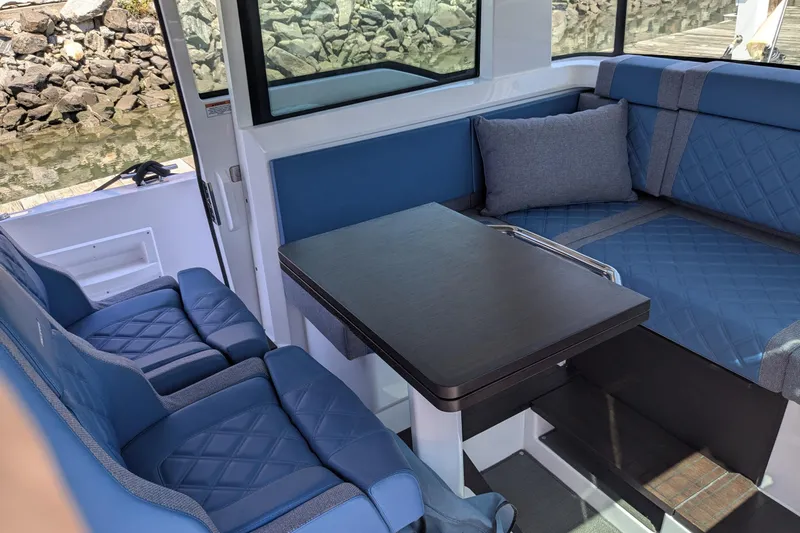 Nocellara De Belice Yacht Photos Pics 2024 Axopar 37 Cross Cabin interior with blue bench seating and table.