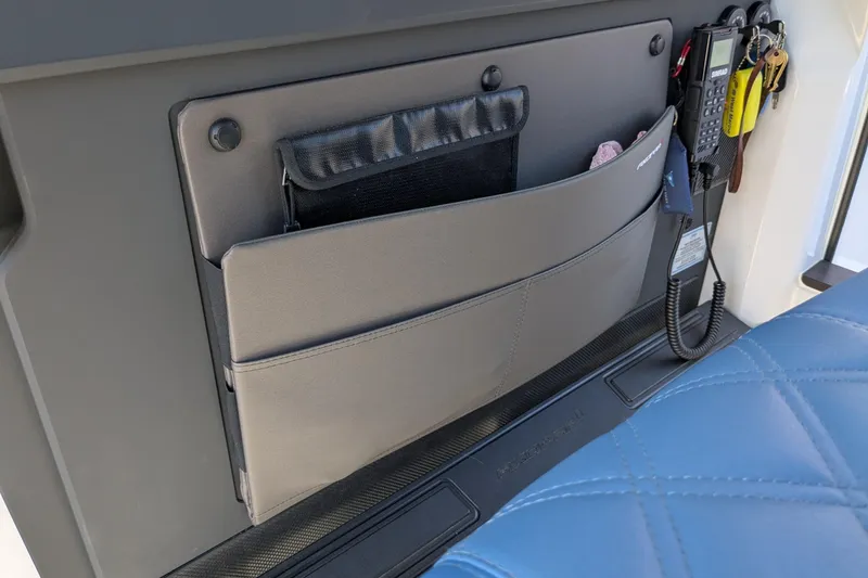 Nocellara De Belice Yacht Photos Pics 2024 Axopar 37 Cross Cabin interior storage with radio and keys, featuring blue quilted seating.