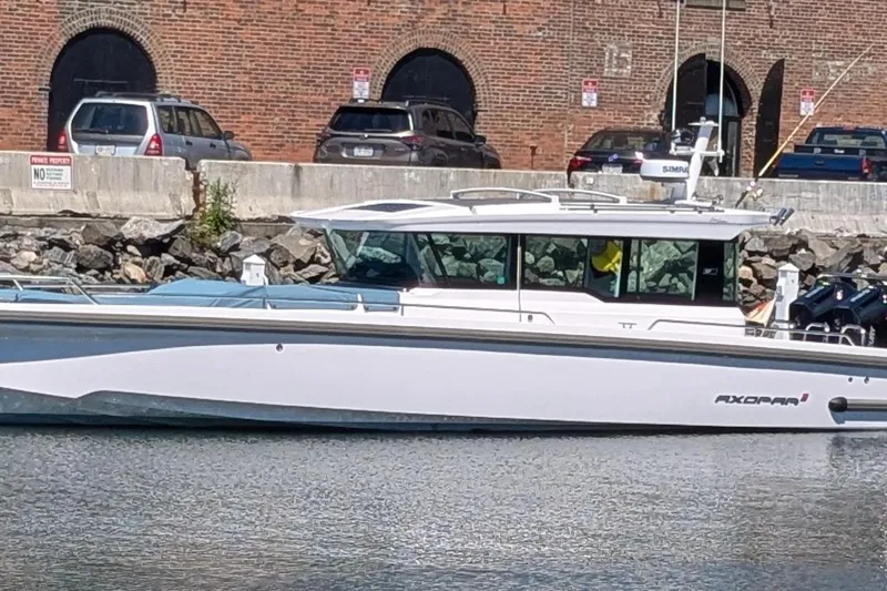 Nocellara De Belice Yacht Photos Pics 2024 Axopar 37 Cross Cabin boat with bench seat, docked by a brick wall.