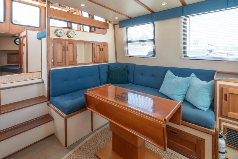 Cinnamon Girl Yacht Photos Pics Interior of 2000 Nordic Tug 32 with blue seating and wooden accents.