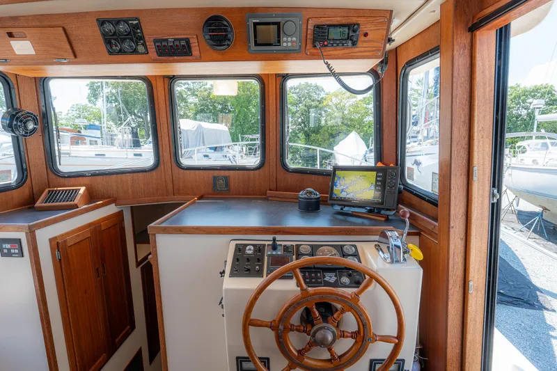 Cinnamon Girl Yacht Photos Pics Interior of a 2000 Nordic Tug 32 boat, featuring a wooden helm and navigation equipment.
