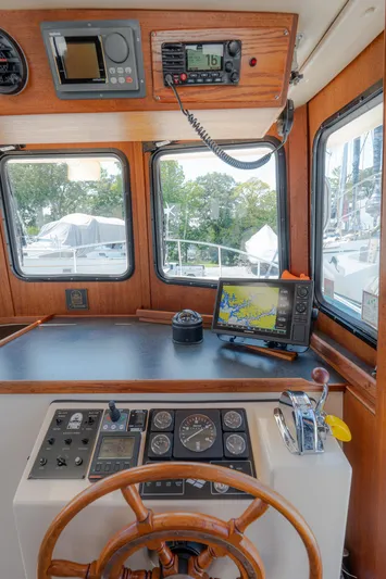 Cinnamon Girl Yacht Photos Pics Pilothouse of 2000 Nordic Tug 32 with navigation equipment and wooden steering wheel.