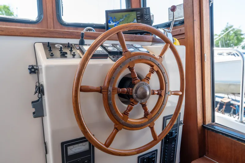 Cinnamon Girl Yacht Photos Pics Wooden steering wheel on a 2000 Nordic Tug 32 boat's control panel.