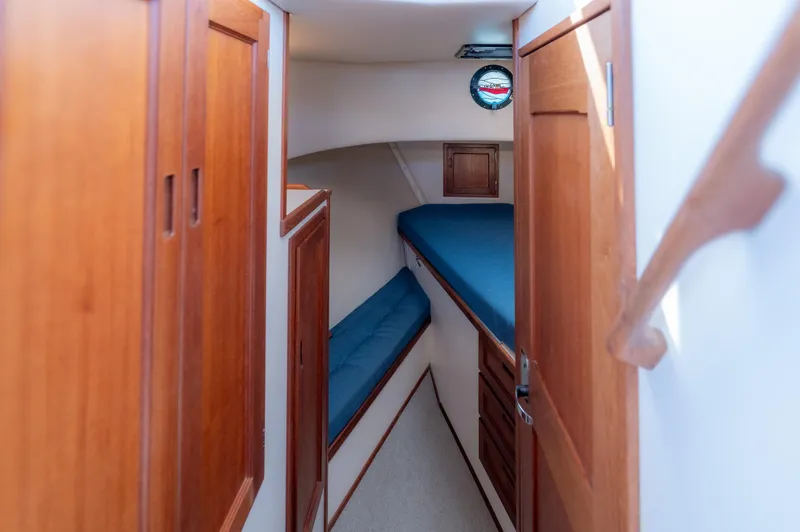 Cinnamon Girl Yacht Photos Pics Interior cabin of a 2000 Nordic Tug 32 with wooden cabinetry and blue bedding.