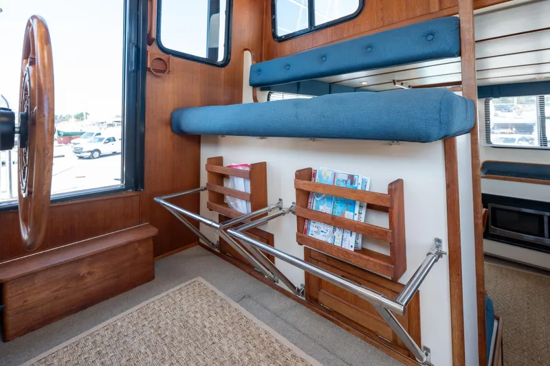 Cinnamon Girl Yacht Photos Pics Interior of a 2000 Nordic Tug 32, featuring a wooden helm and blue cushioned seating.