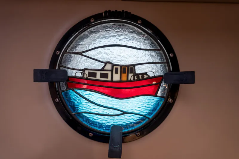 Cinnamon Girl Yacht Photos Pics Stained glass porthole featuring a red boat, Nordic Tug 32, 2000 model.