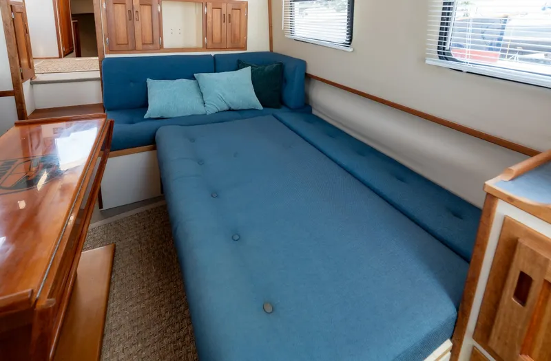 Cinnamon Girl Yacht Photos Pics Interior of a 2000 Nordic Tug 32 with blue seating and wooden accents.
