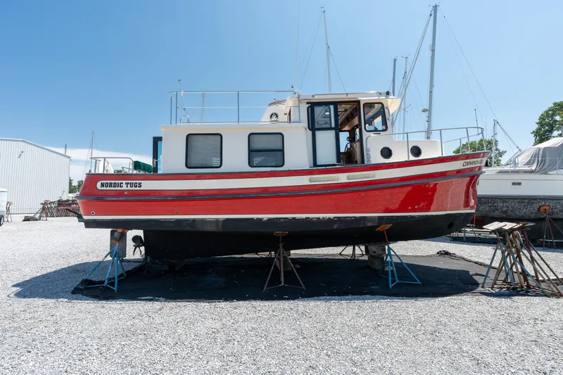 Cinnamon Girl Yacht Photos Pics 2000 Nordic Tug 32 boat on stands in a boatyard under clear blue sky.