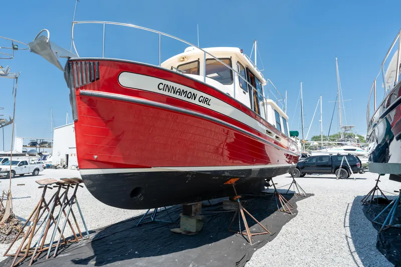Cinnamon Girl Yacht Photos Pics Red 2000 Nordic Tug 32 boat named "Cinnamon Girl" on dry dock under clear blue sky.