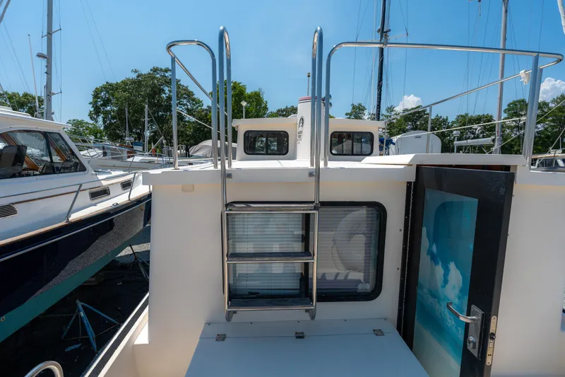 Cinnamon Girl Yacht Photos Pics Nordic Tug 32 boat deck with ladder, 2000 model, docked under clear blue sky.