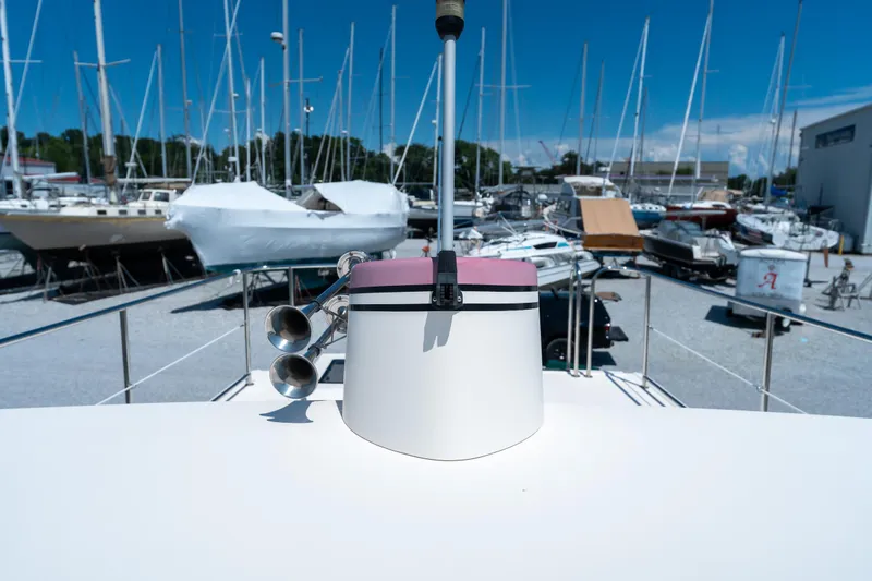 Cinnamon Girl Yacht Photos Pics Nordic Tug 32 (2000) on deck, surrounded by various boats in a marina.