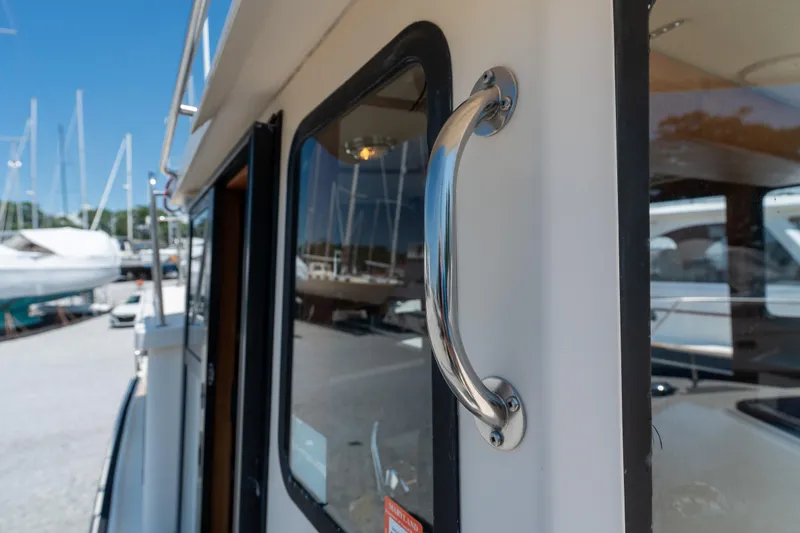 Cinnamon Girl Yacht Photos Pics Close-up of a 2000 Nordic Tug 32 boat handle and window in a marina.