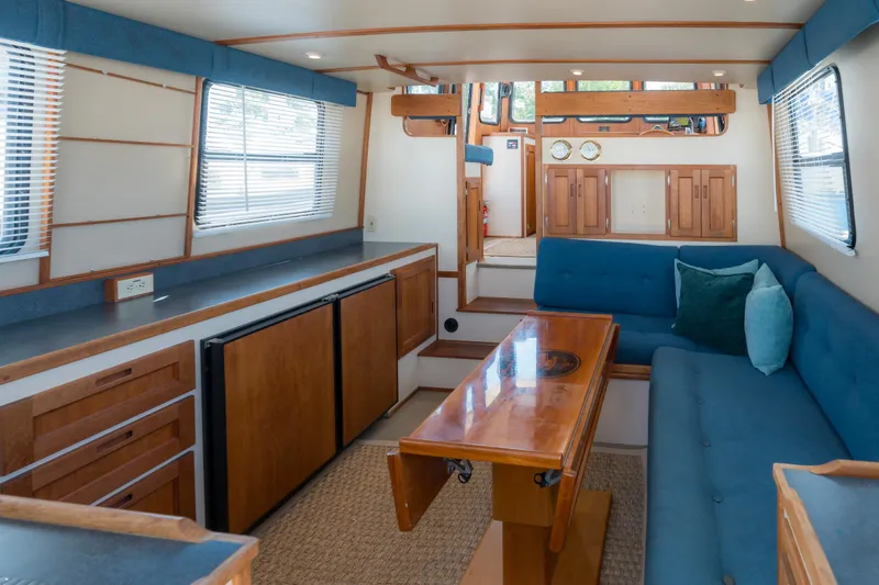 Cinnamon Girl Yacht Photos Pics Interior of a 2000 Nordic Tug 32, featuring blue seating and wooden cabinetry.