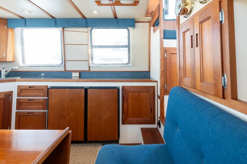 Cinnamon Girl Yacht Photos Pics Interior of 2000 Nordic Tug 32 with wooden cabinetry and blue seating.