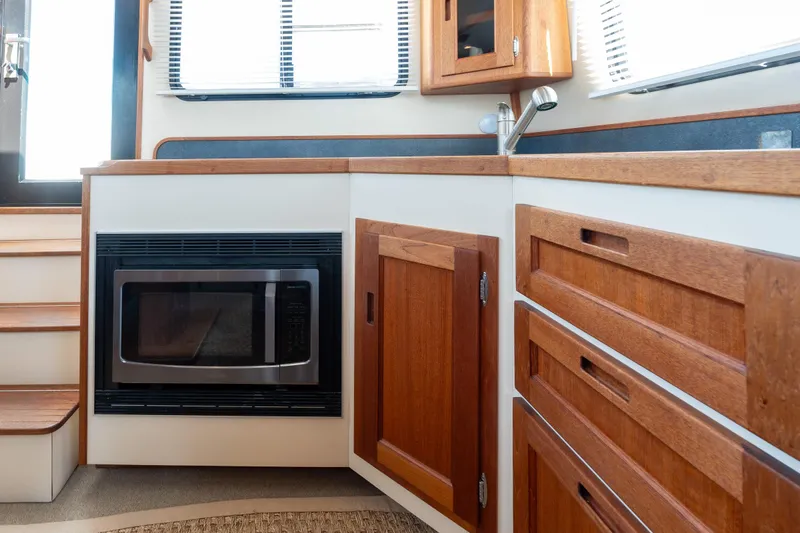 Cinnamon Girl Yacht Photos Pics Interior of 2000 Nordic Tug 32, featuring a compact kitchen with wood cabinetry and microwave.