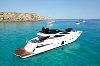Luxury 2008 Pershing 90 yacht on clear turquoise waters near rocky coastline.
