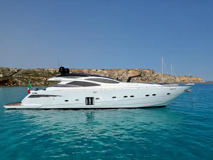 Thyke III Yacht Photos Pics 2008 Pershing 90 yacht on clear blue water with rocky coastline in the background.