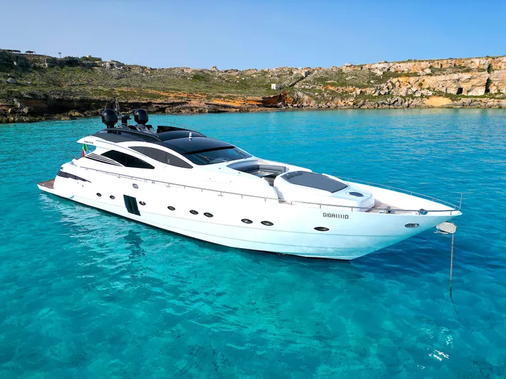 Thyke III Yacht Photos Pics 2008 Pershing 90 yacht in clear turquoise waters near rocky coastline.