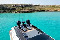 2008 Pershing 90 yacht on turquoise waters near rocky coastline.