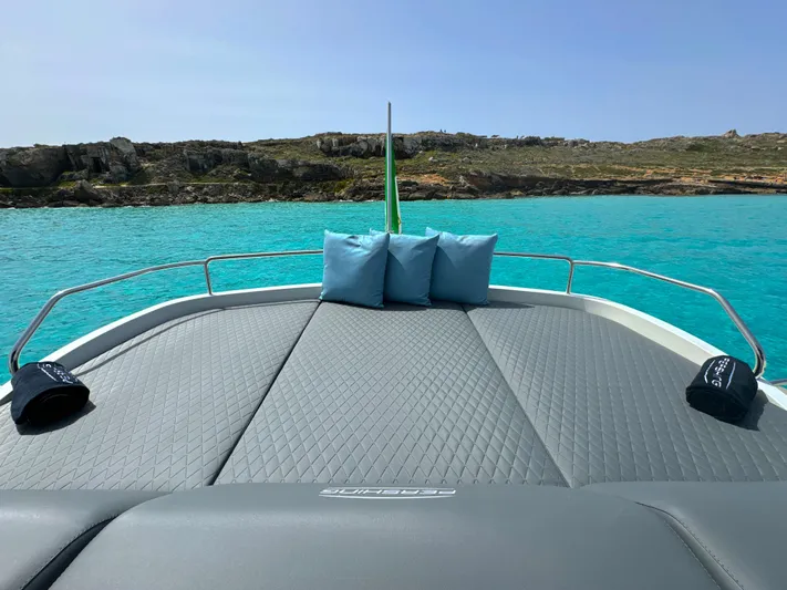 Thyke III Yacht Photos Pics 2008 Pershing 90 yacht deck with cushions, overlooking turquoise water and rocky shoreline.