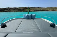 2008 Pershing 90 yacht deck with cushions, overlooking turquoise water and rocky shoreline.