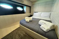 Luxurious bedroom interior of 2008 Pershing 90 yacht with porthole windows and plush bedding.