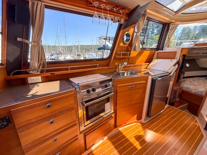  Yacht Photos Pics 2018 Ranger Tugs R-29 S interior with kitchen, wood cabinetry, and marina view.