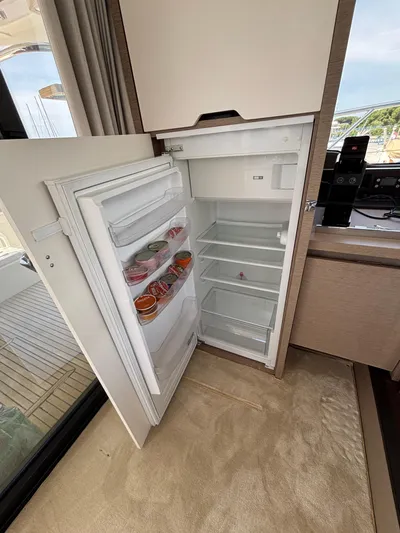  Yacht Photos Pics Open refrigerator inside 2020 Jeanneau Prestige 460 yacht, showing stocked shelves and modern interior.