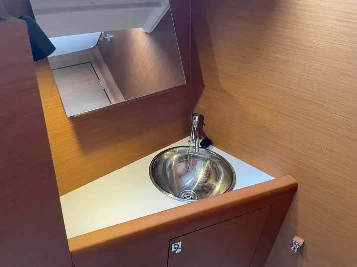  Yacht Photos Pics 2023 Jeanneau Sun Odyssey 349 bathroom with sleek sink and wooden cabinetry.