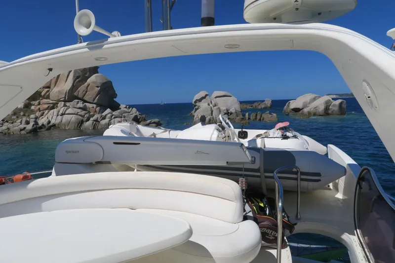  Yacht Photos Pics Azimut 55 yacht from 2004, anchored near rocky coastline with clear blue water.