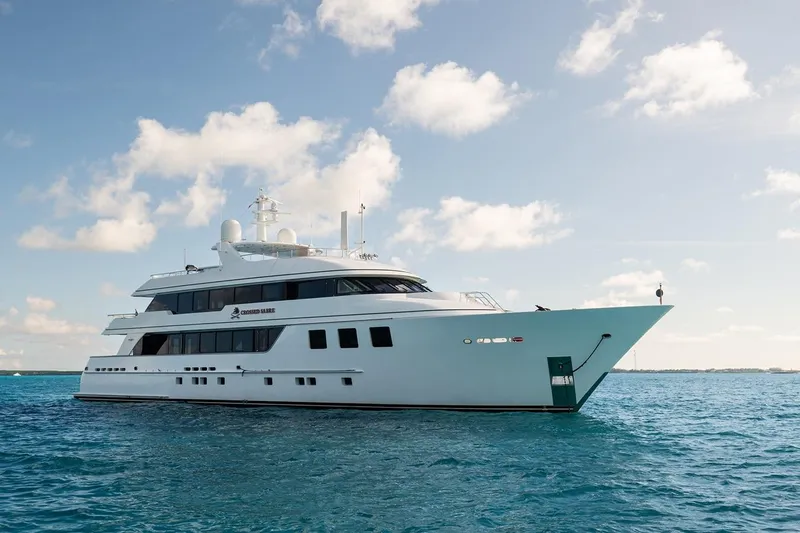 Crossed Sabre Yacht Photos Pics Luxurious 2006 Burger Trideck yacht cruising on clear blue waters under a sunny sky.