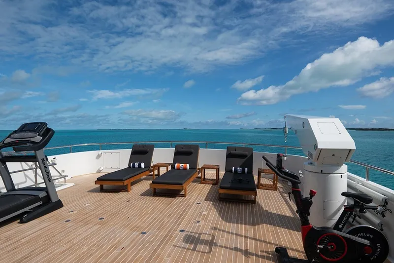 Crossed Sabre Yacht Photos Pics Luxurious 2006 Burger Trideck yacht deck with loungers, exercise equipment, and ocean view.