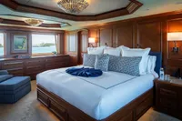 Luxurious bedroom on 2006 Burger Trideck yacht with elegant wood paneling and ocean view.