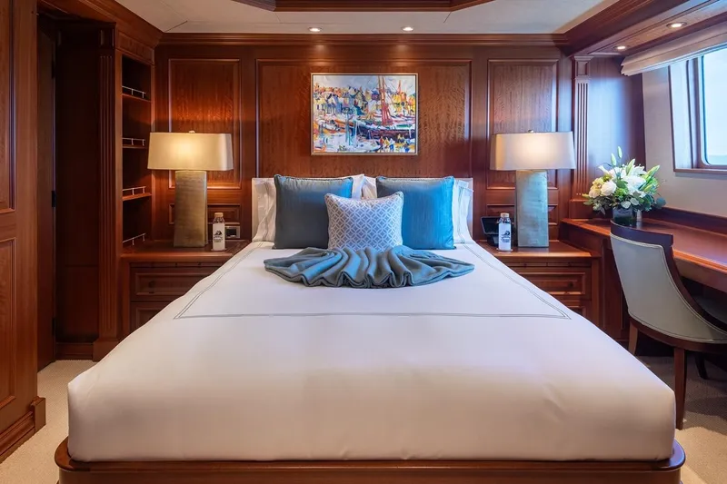 Crossed Sabre Yacht Photos Pics Luxurious yacht bedroom with elegant wood paneling, plush bedding, and decorative pillows.