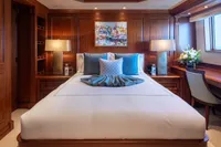 Luxurious yacht bedroom with elegant wood paneling, plush bedding, and decorative pillows.