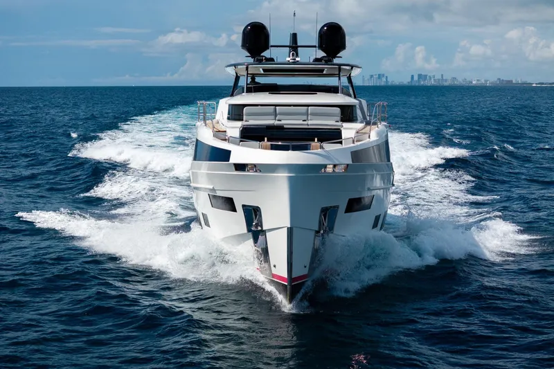  Yacht Photos Pics Luxurious 2021 Sirena 88 yacht cruising on open ocean with city skyline in background.