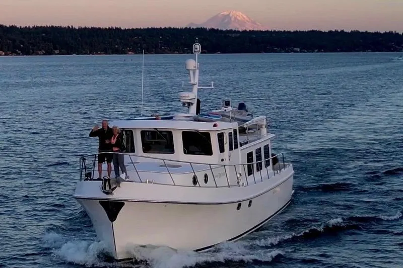 Pacific Rose Yacht Photos Pics 2009 American Tug 49 Limited cruising on a scenic waterway with mountain backdrop.