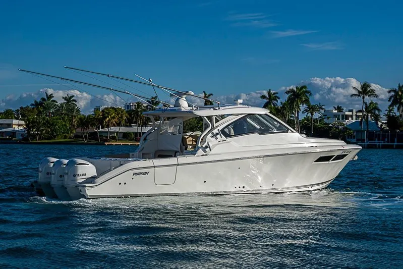  Yacht Photos Pics 2020 Pursuit DC 365 Dual Console boat cruising on a sunny day with palm trees in background.