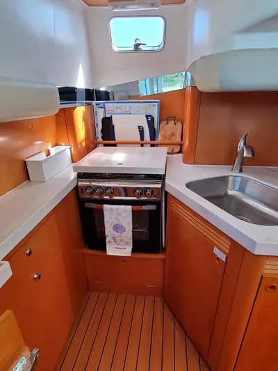My Three Girls Yacht Photos Pics 2004 Lagoon 43 PC yacht kitchen with stove, sink, and wooden cabinetry.