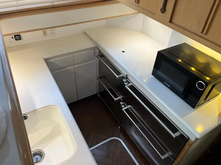 Amen Corner Yacht Photos Pics Compact kitchen area in a 1995 Hatteras 45 Convertible yacht with microwave and sink.