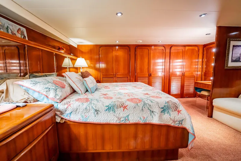 Jubilee Yacht Photos Pics Luxurious bedroom in 1989 Viking 63 Motor Yacht with elegant wood paneling and cozy bedding.