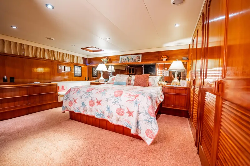 Jubilee Yacht Photos Pics Luxurious bedroom interior of 1989 Viking 63 Motor Yacht with elegant wood finishes and cozy decor.