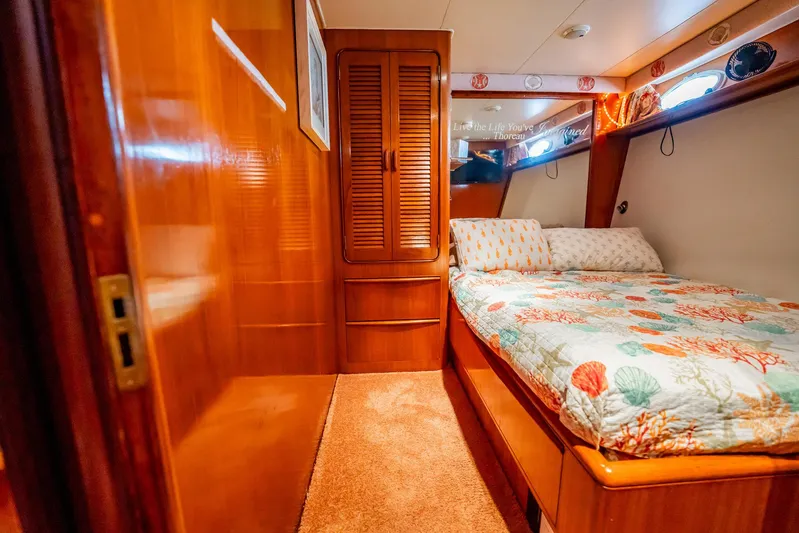 Jubilee Yacht Photos Pics Cozy bedroom interior of 1989 Viking 63 Motor Yacht with wooden cabinetry and nautical bedding.