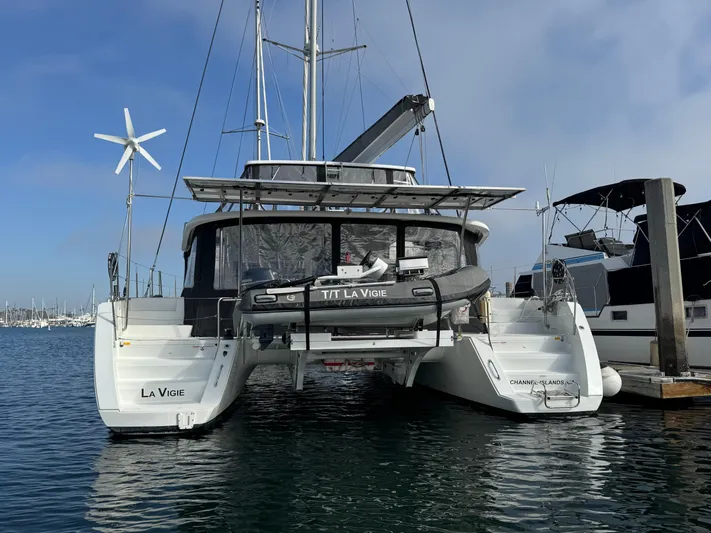 La Vigie Yacht Photos Pics 2018 Lagoon 450 F catamaran docked at marina, featuring a dinghy and wind turbine.
