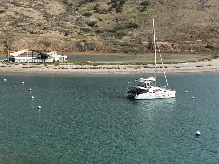 La Vigie Yacht Photos Pics 2018 Lagoon 450 F catamaran anchored near a scenic shoreline with hills.