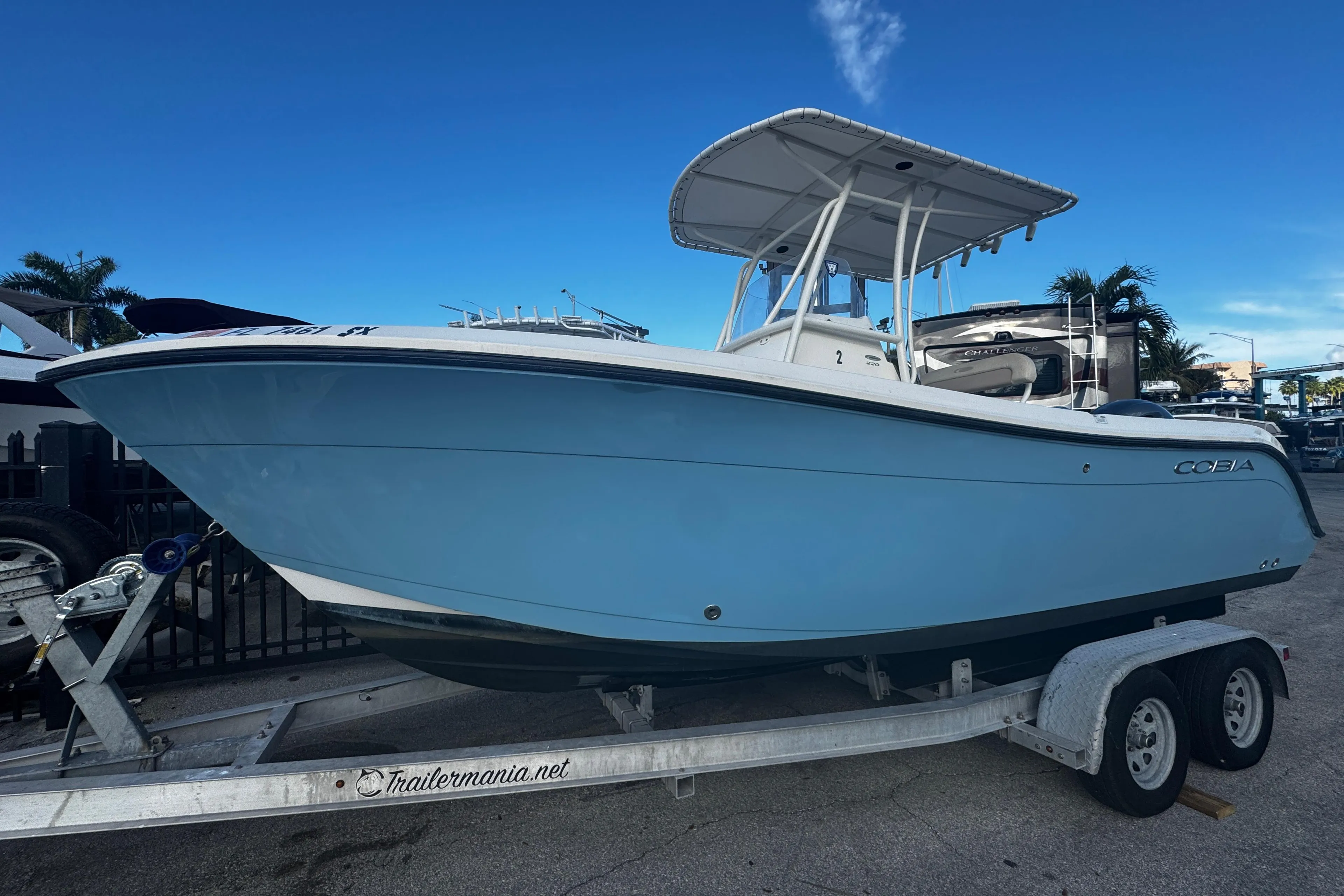 2021 Cobia 220 Center Console boat on trailer, blue hull, clear sky background.