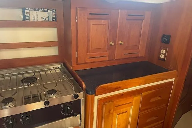 Aquavit Yacht Photos Pics Wooden kitchen interior of 2001 Tartan 3700 yacht with stove and cabinets.