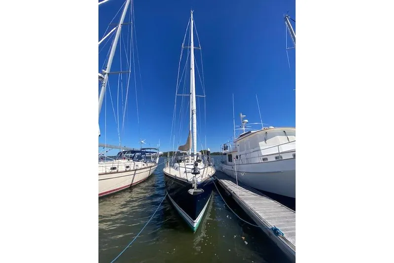 Aquavit Yacht Photos Pics Sailboat Tartan 3700 (2001) docked between yachts under clear blue sky.