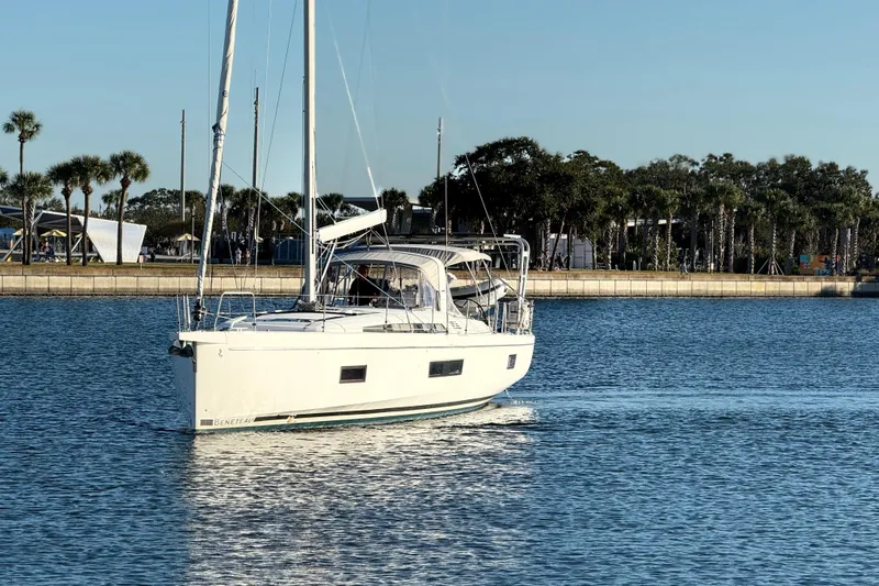  Yacht Photos Pics 2020 Beneteau Oceanis 51.1 sailing in calm waters near a palm-lined shore.